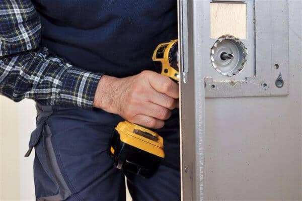 Locksmith drilling into door to install lock